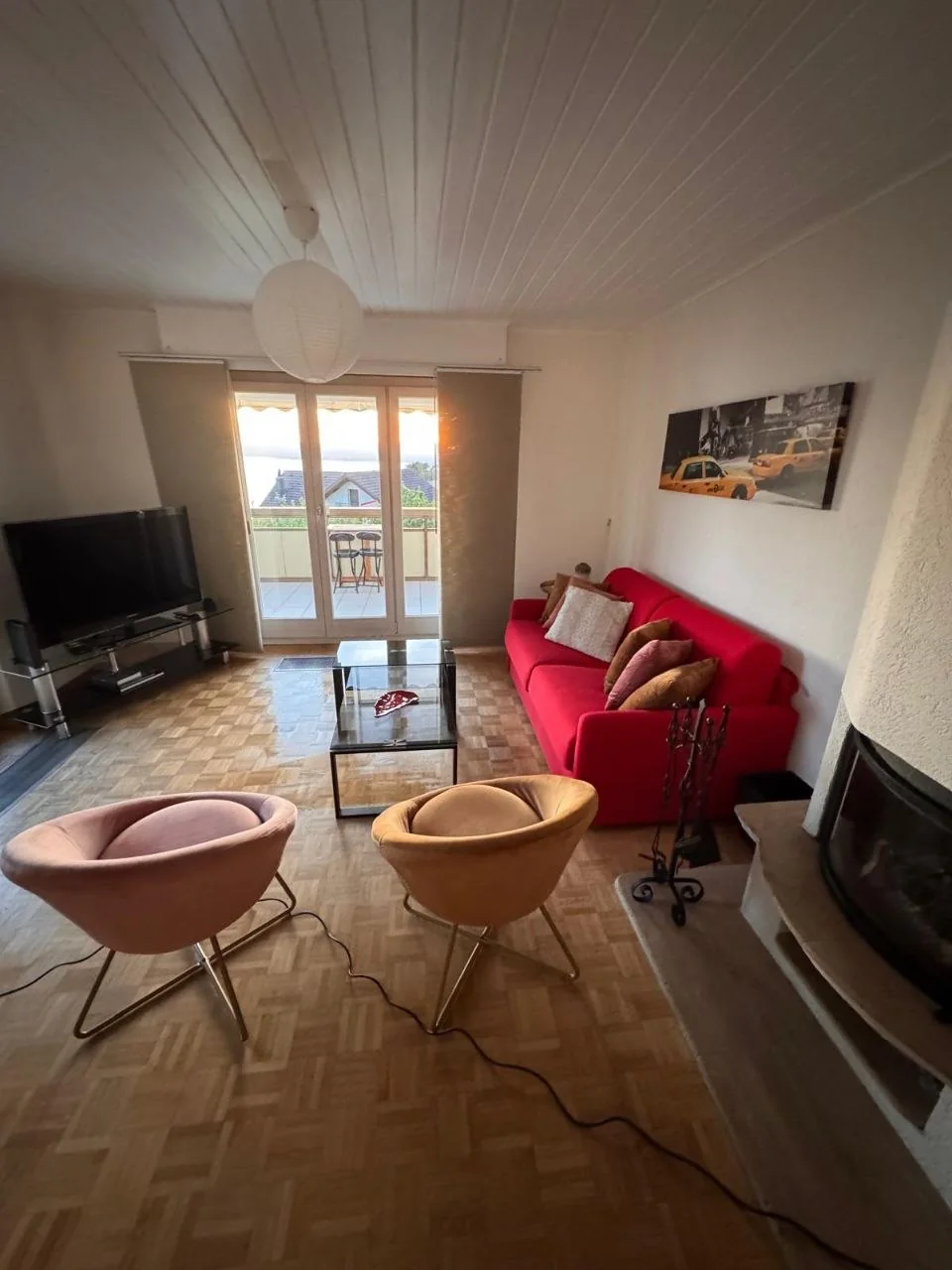Salon avec canapé rouge et accès au balcon