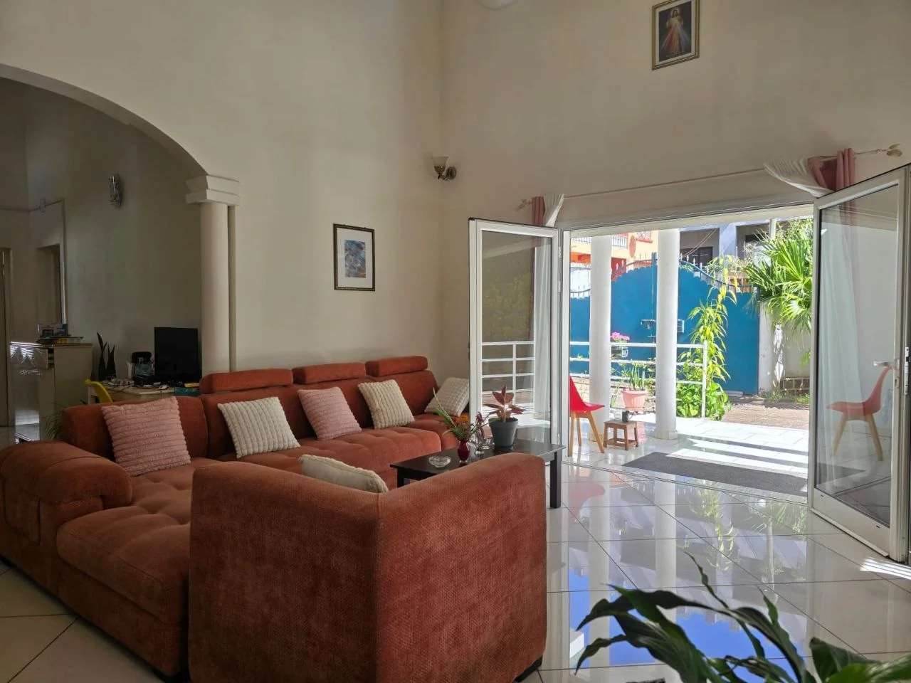 Salon avec canapé et baie vitrée ouverte sur une terrasse