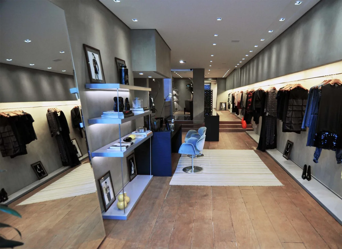 Intérieur d’une boutique de vêtements avec portants, étagères et espace de circulation dégagé.