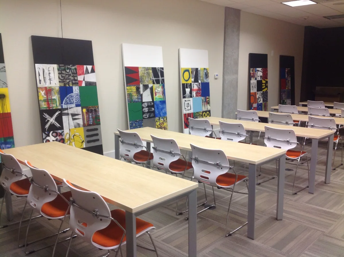 Salle de classe vide avec tables claires et chaises blanches à assise orange.